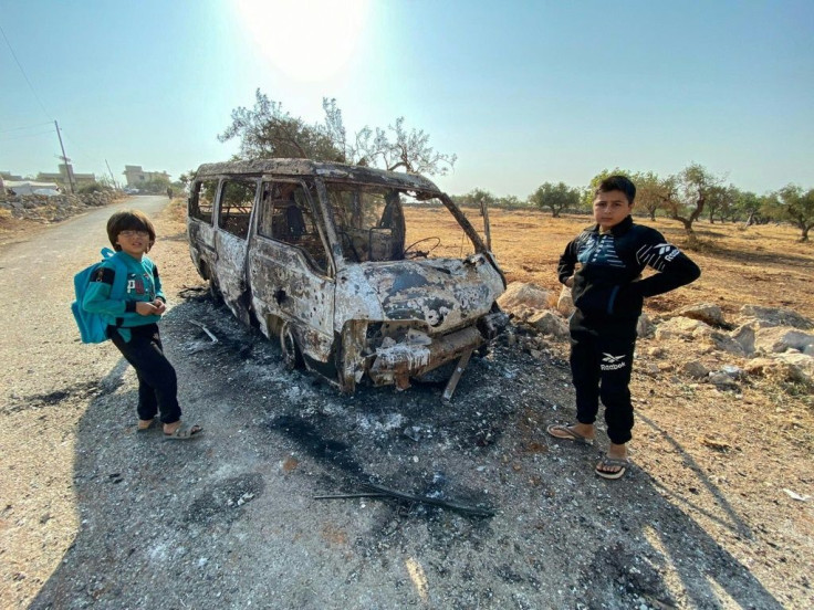 Syrian children stand next to a burnt vehicle on October 27, 2019 near where the operation reportedly took place