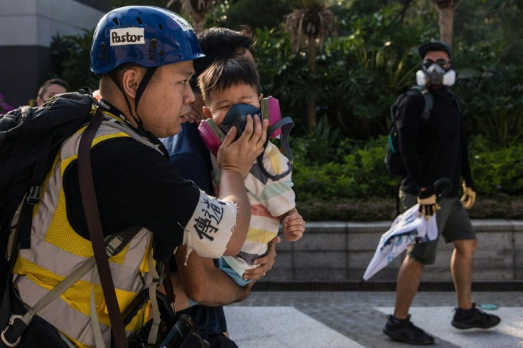 A man puts a gas mask on a young boy after police fired tear gas to disperse protesters, the latest clashes in nearly five months of unrest