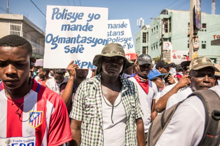 Police officers hold a placard with the slogan, "Policemen demand higher wages" during a demonstration by police and their supporters in Port-au-Prince