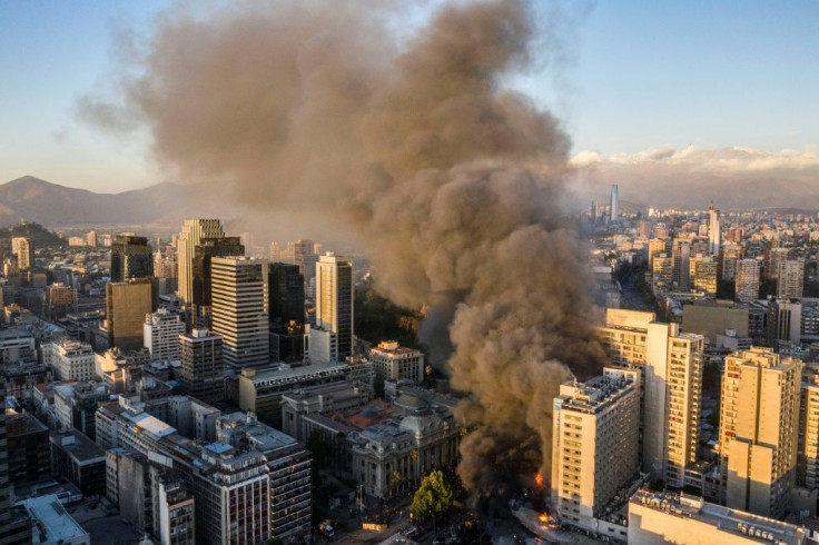 Smoke billows from a building on fire near where protesters were demonstrating in Santiago, on October 28, 2019