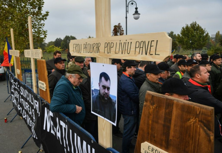 Forest guards stand next to wooden crosses bearing the names of their killed colleagues during a protest near the Romanian Parliament building in Bucharest
