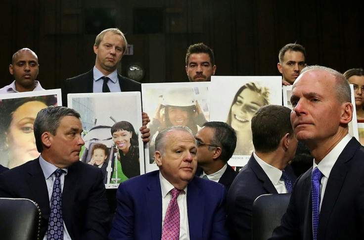Family members of those who died aboard Ethiopian Airlines Flight 302 hold photographs of their loved ones as Dennis Muilenburg (R), president and CEO of the Boeing Company, testifies before the Senate Commerce Committee