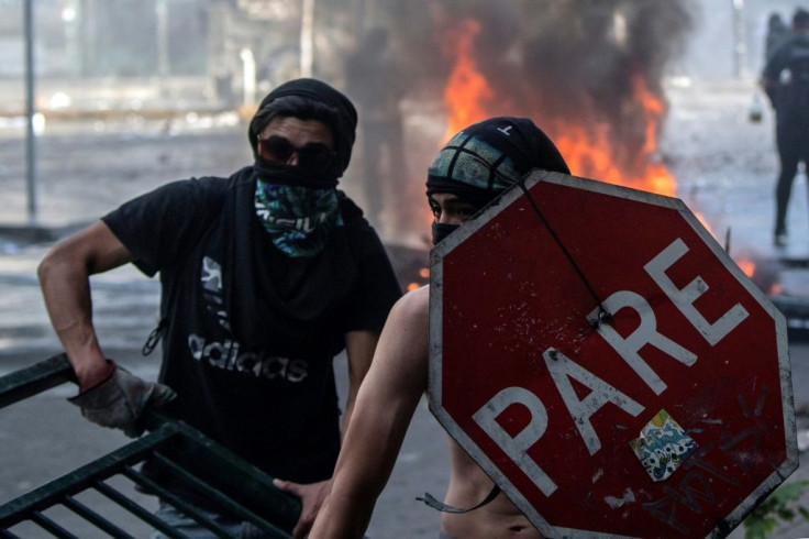 Demonstrators clash with riot police near the presidential palace in Santiago, on October 29, 2019