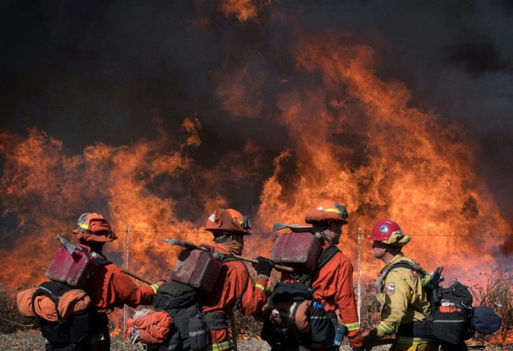 Firefighters walk the road leading to the Reagan Presidential Library during the Easy Fire in Simi Valley, California on October 30, 2019