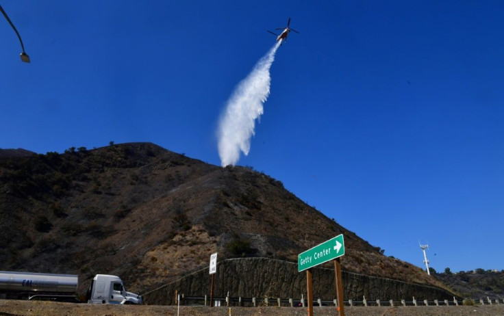 A helicopter makes a water drop over hillsides in the Los Angeles area on October 29, 2019