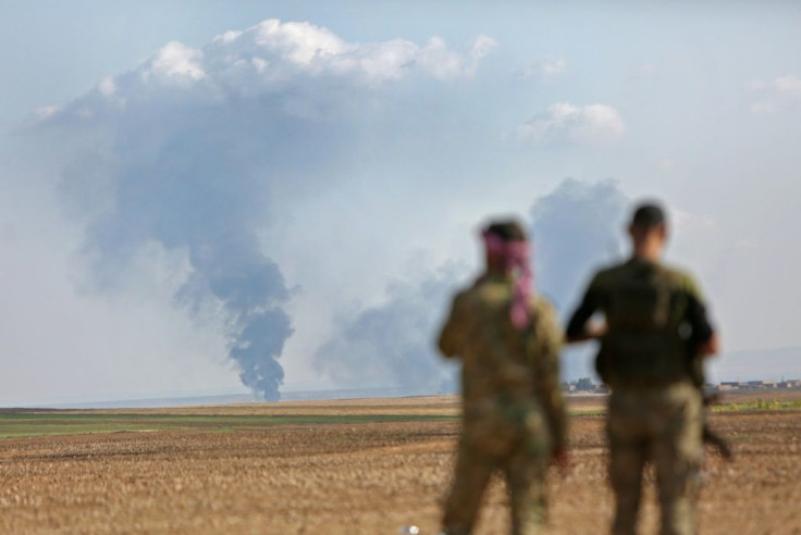 Turkey-backed Syrian fighters watch as smoke billows in the distance during clashes between Syrian regime forces, and Turkish forces, 15kms east of the northeastern town of Ras al-Ein, on October 30, 2019