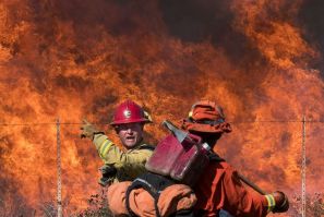 A firefighter (L) speaks to an inmate firefighter as they prepare to put out flames on the road leading to the Reagan Library during the Easy Fire in Simi Valley, California on October 30, 2019