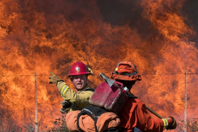 A firefighter (L) speaks to an inmate firefighter as they prepare to put out flames on the road leading to the Reagan Library during the Easy Fire in Simi Valley, California on October 30, 2019