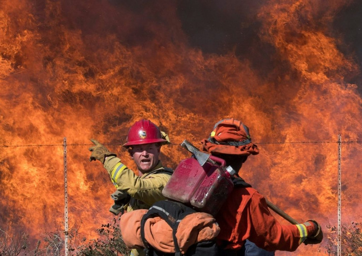 A firefighter (L) speaks to an inmate firefighter as they prepare to put out flames on the road leading to the Reagan Library during the Easy Fire in Simi Valley, California on October 30, 2019