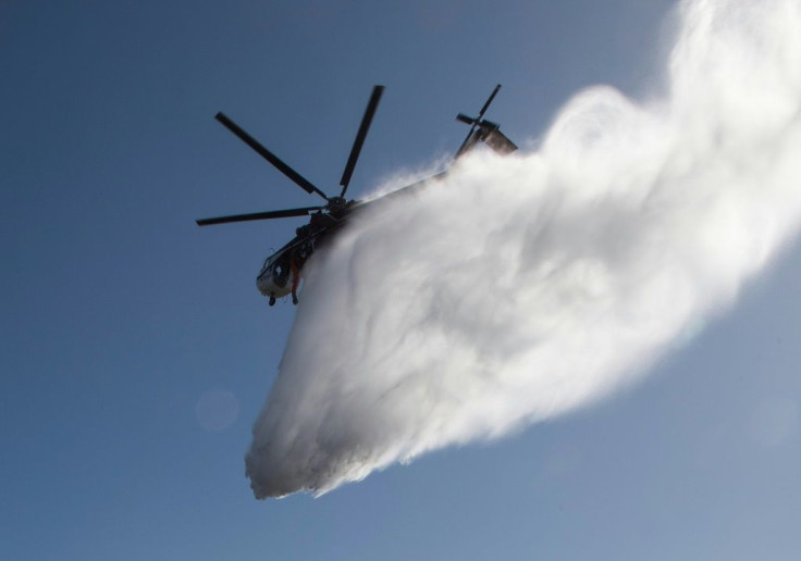 Water dropped by a helicopter lands on flames burning near the Reagan Library during the Easy Fire in Simi Valley, California on October 30, 2019