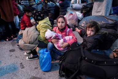 Refugees wait to board buses after their arrival from Lesbos to the port of Piraeus near Athens
