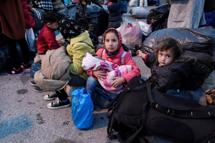 Refugees wait to board buses after their arrival from Lesbos to the port of Piraeus near Athens