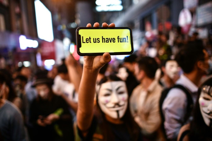 A masked Halloween reveller flashes a phone message to police in the Lan Kwai Fong entertainment area of Hong Kong