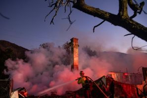 A firefighter douses a smoldering home during the Hillside Fire in the North Park neighborhood of San Bernardino, California on October 31, 2019.