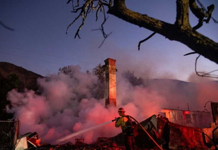 A firefighter douses a smoldering home during the Hillside Fire in the North Park neighborhood of San Bernardino, California on October 31, 2019.