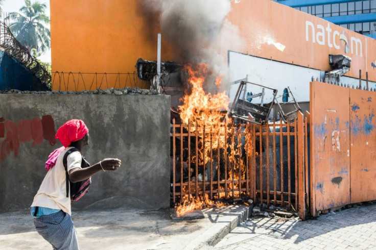 A man watches a fire as protesters, medical professionals and political opponents demonstrate in Port-au-Prince on October 30