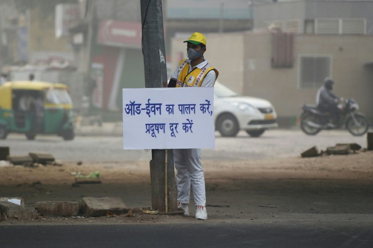 A volunteer in smog-choked New Delhi displays a placard warning drivers of the new odd-even number plate system in effect that seeks to reduce air pollution in the capital