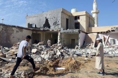 Libyans check the site of an air strike in which three children were killed and others wounded on the southern outskirts of the capital Tripoli