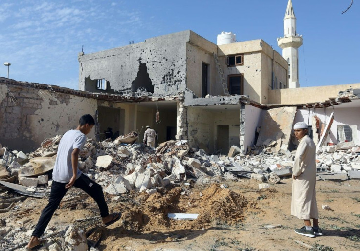 Libyans check the site of an air strike in which three children were killed and others wounded on the southern outskirts of the capital Tripoli