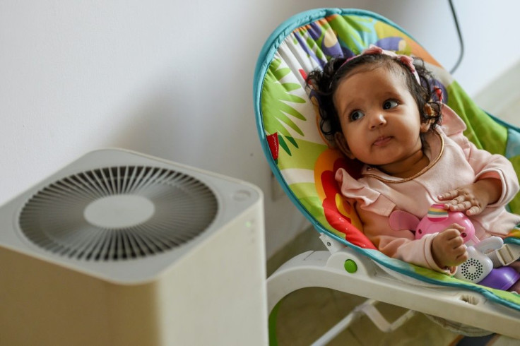 Six-month-old Ayesha rests near an air purifier at her home in Delhi