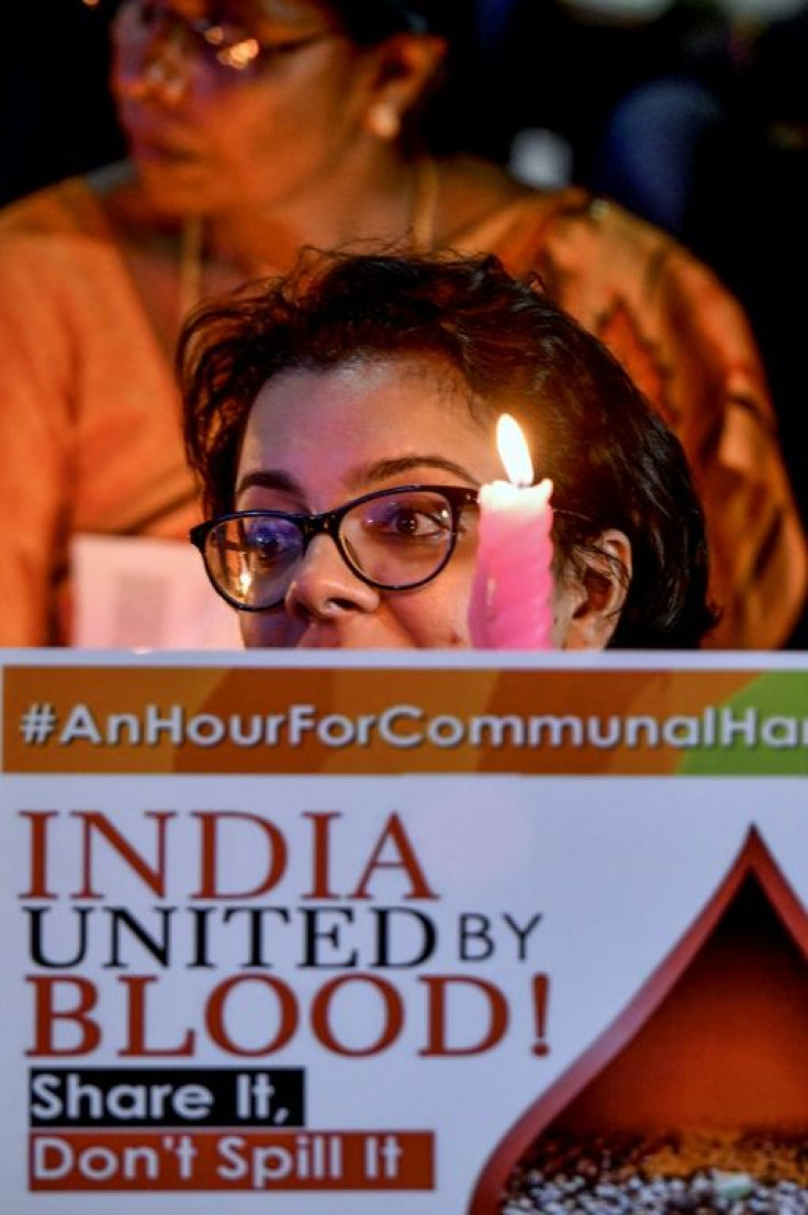 An activist belonging to 'People for Peace and Justice' holds a placard as she participates in a candlelight vigil in the Indian city of Bangalore ahead of the Ayodhya verdict
