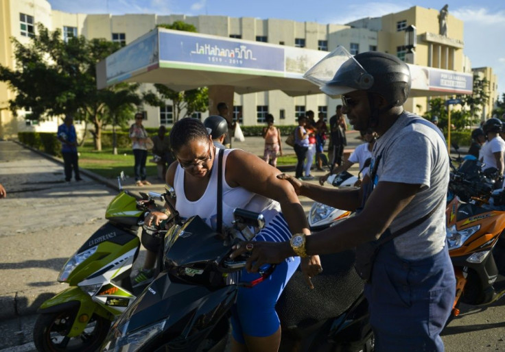 Members of the Electric Motorcycles of Cuba club ride passengers home