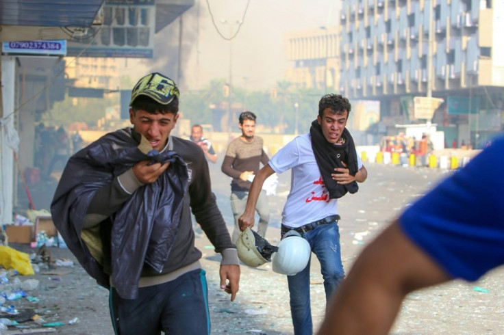 Iraqi protesters run for cover in the capital Baghdad as security fire tear gas at them in a bid to clear protest sites