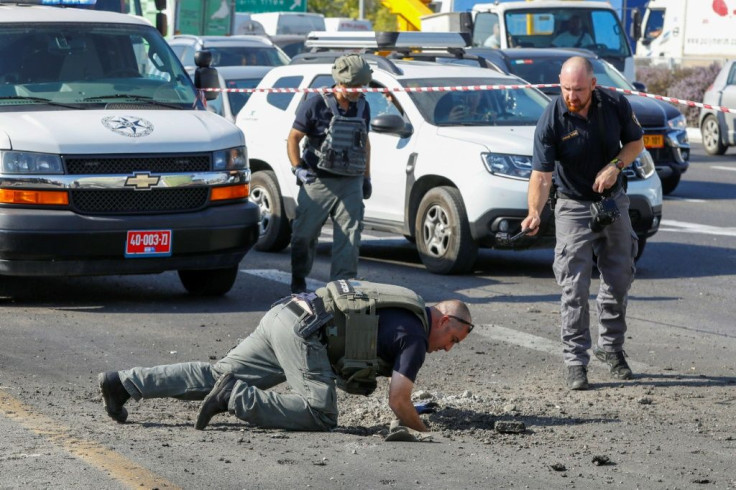 Israeli police sappers inspect a hole in the highway at a busy junction after a rocket fired from Gaza narrowly misses motorists