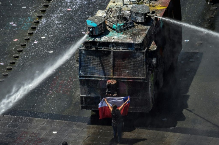 A demonstrator stands in front of police water cannon in Santiago, Chile, which has been rocked by protests