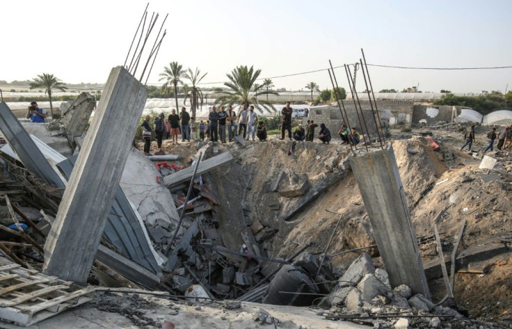 Palestinians gather around the remains of a house destroyed in an Israeli air strike on the city of Khan Yunis in the southern Gaza Strip