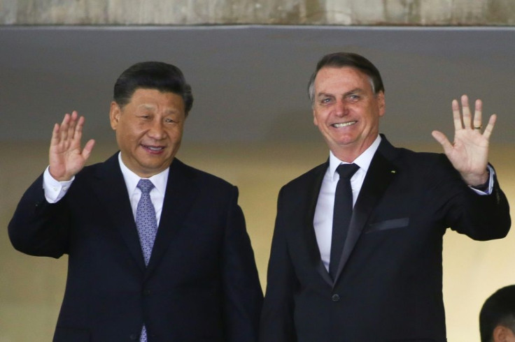 China's President Xi Jinping (L) and Brazil's President Jair Bolsonaro (R) wave before a bilateral meeting in Brasilia ahead of a summit of the BRICS countries