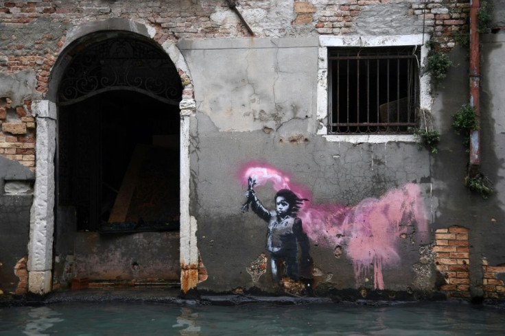 An artwork by Banksy portraying a migrant child wearing a lifejacket and holding a neon pink flare remained just above water during the tide