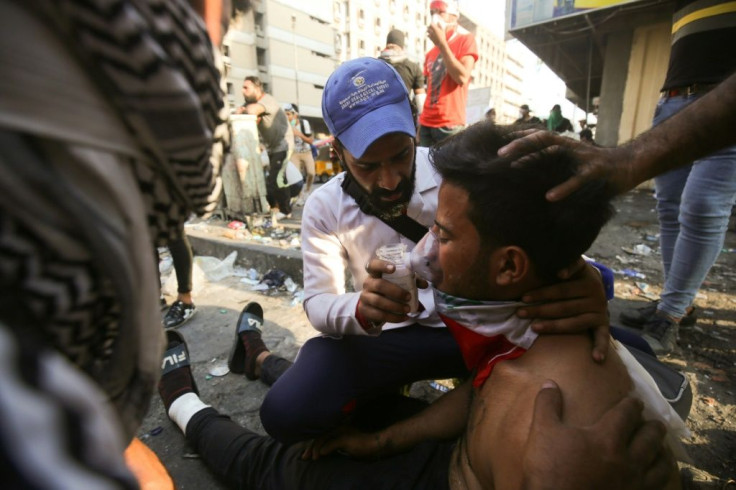 An Iraqi volunteer helps a protester overcome by tear gas during clashes with security forces near Baghdad's Tahrir Square