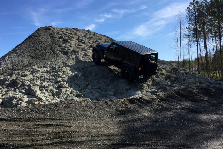 A driver attempts to ride over a mound of asphalt during a media tour of a new training facility for US personnel overseas