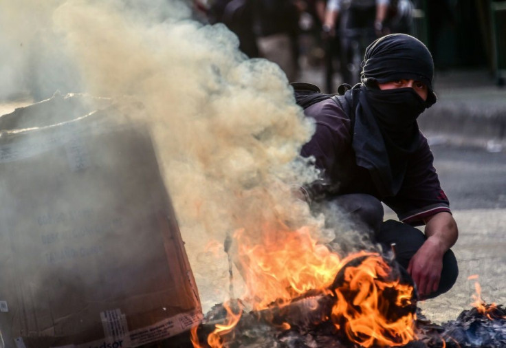 A demonstrator protesting against the economic policies of the Chilean government kneels by a burning barricade during clashes with riot police in Santiago, on November 4, 2019