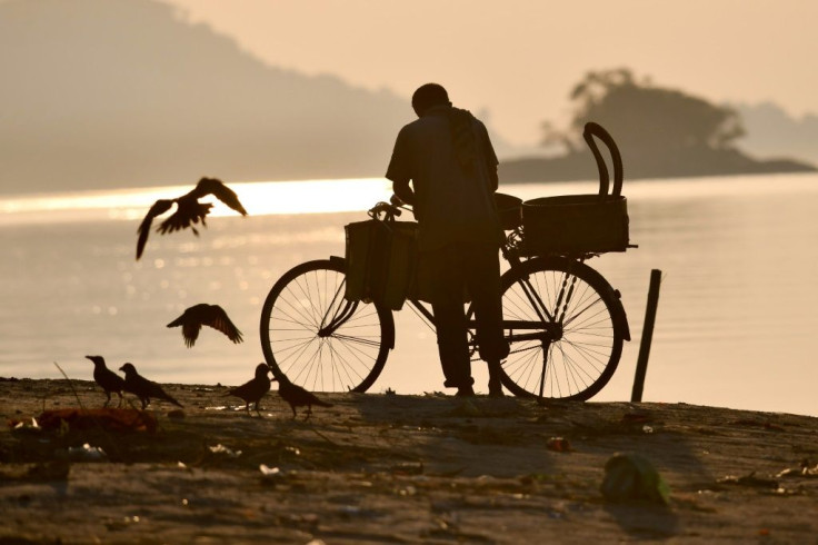 A fish vendor cleans his bicycle and basket after selling his catch on the banks of the river Brahmaputra in Guwahati