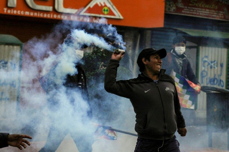A supporter of Bolivian ex-president Evo Morales throws a tear gas canister back at riot police during a protest against the interim government in La Paz on November 15, 2019