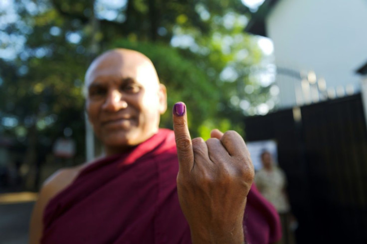 A Buddhist monk shows his inked finger after casting his vote