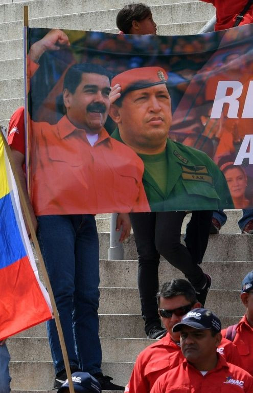 People hold a banner with images of Venezuelan President Nicolas Maduro (L) and late president Hugo Chavez during a pro-government demonstration in Caracas
