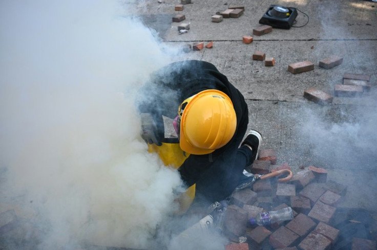 A protester attempts to snuff out a tear gas canister fired by police