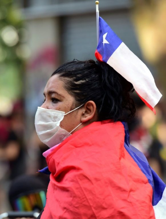 A woman wrapped in a Chilean flag sits during a protest against the government in Santiago on Monday
