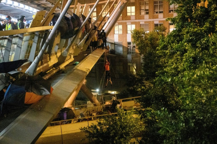 A protester (C) lowers herself down a rope from a bridge to a highway to escape from the campus of Hong Kong Polytechnic University