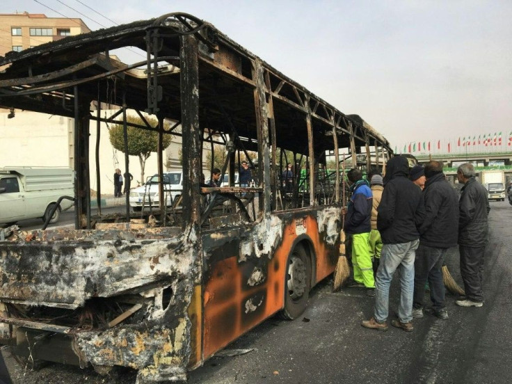 Iranians inspect the wreckage of a bus that was set ablaze by protesters in the central city of Isfahan