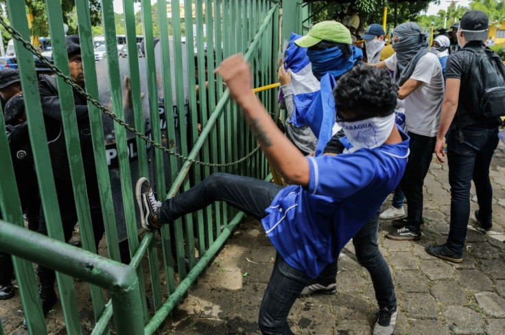 An anti-government protester kicks a riot police shield during a demonstration at the Central American University on Tuesday