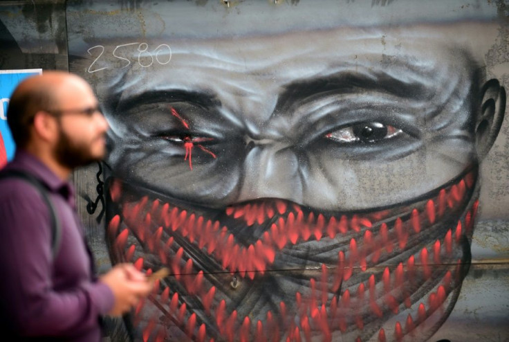 A man walks by graffiti depicting a demonstrator with an injured eye, in clear reference to those hurt in recent clashes, on November 18