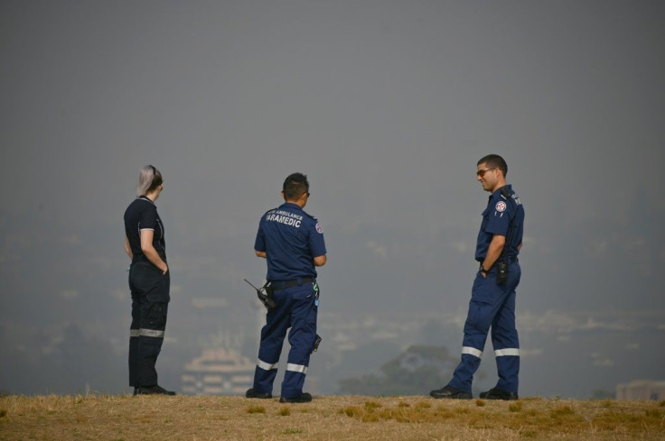 Paramedics take a break as they look out over a smokey haze which blankets Sydney.