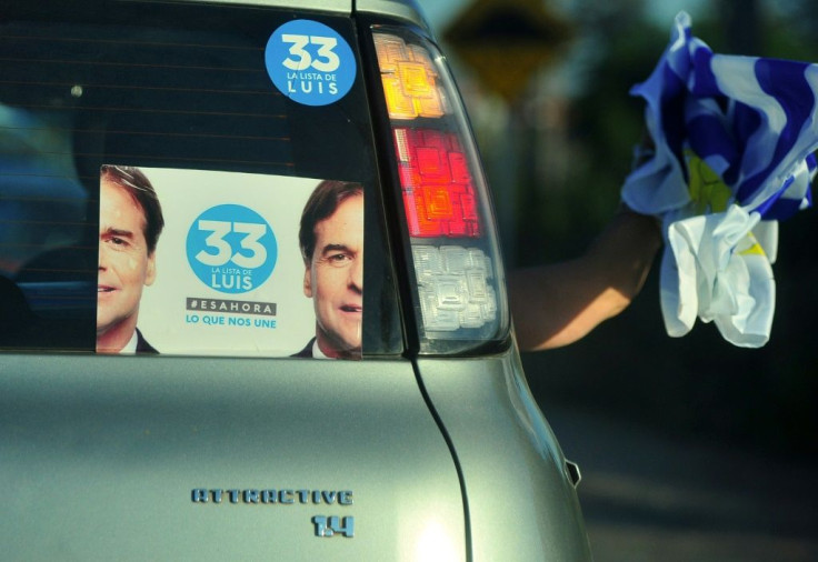 A supporter of Uruguay's presidential candidate for the opposition Partido Nacional party, Luis Lacalle Pou, waves a Uruguayan flag from a car during the closing rally of his campaign