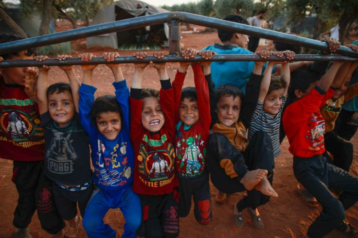 Children swing from the bars of a newly delivered frame before it is even put up to create a new home