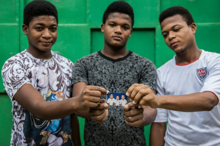 The Bosquet brothers -- Valens (L), Evensky (C) and Reevens -- hold a picture of themselves as toddlers; they still hope to finish high school, even though they are years behind