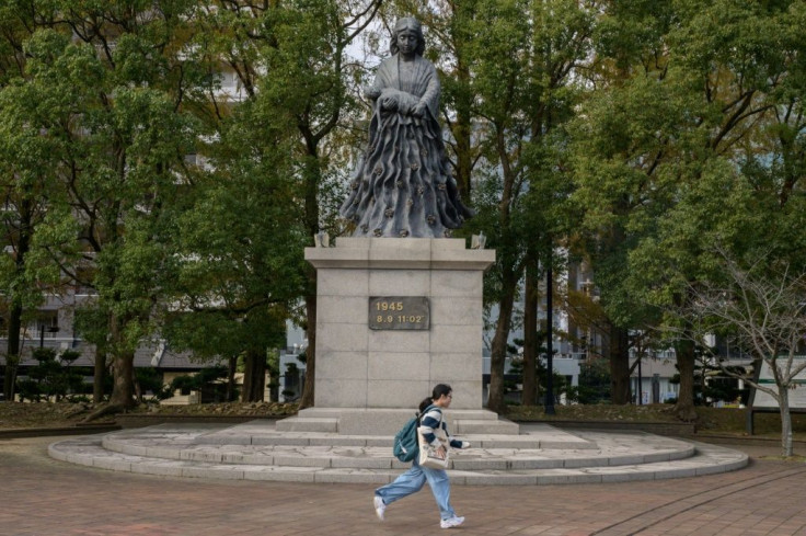 A woman runs past a monument to the atomic bombing in Nagasaki